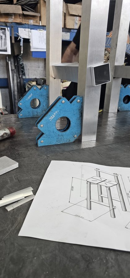 ריתוך מסגרת הכיסא עם זוויתני מגנט, והשרטוט על השולחן