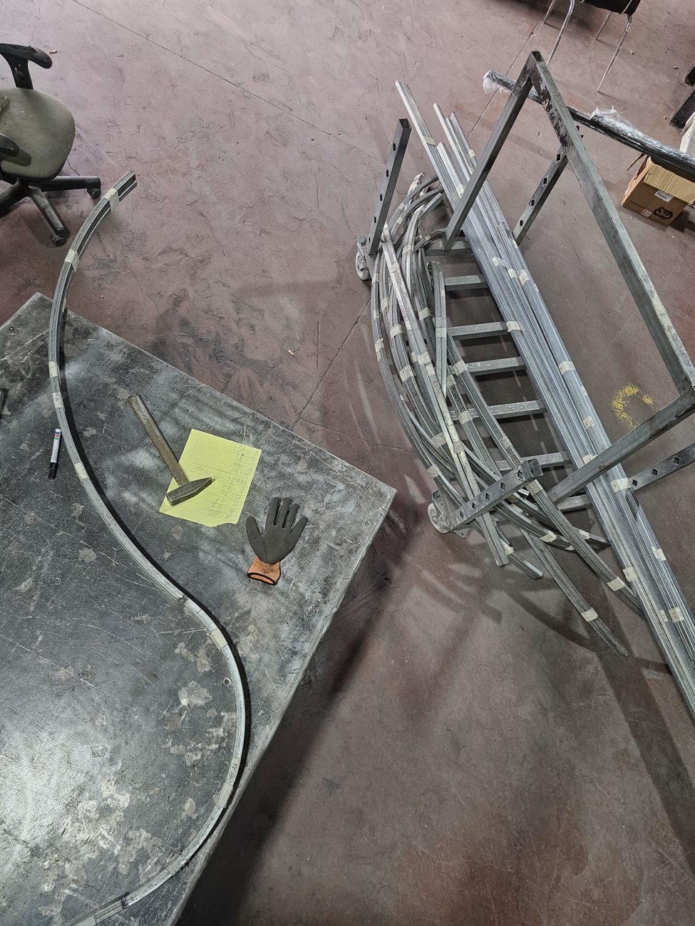 קשת פרופיל על שולחן המסגר ולצדה עגלה עם פרופילים מסומנים