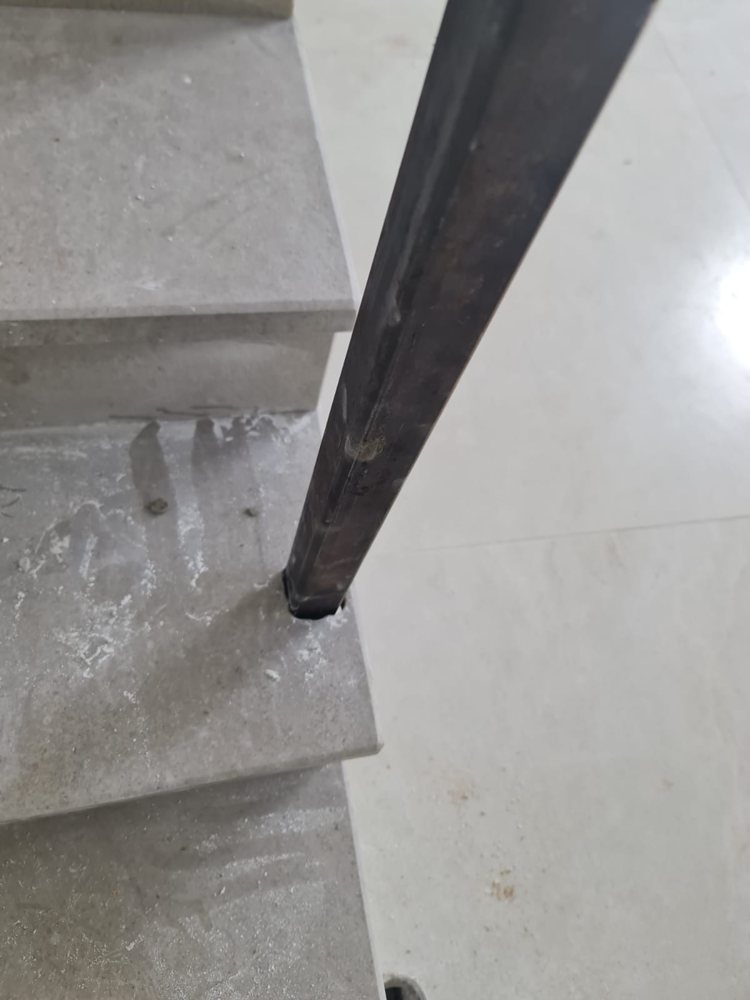 פס המעקה נכנס ישירות לתוך המדרגה, בלי פלטה ובלי בורג גלוי